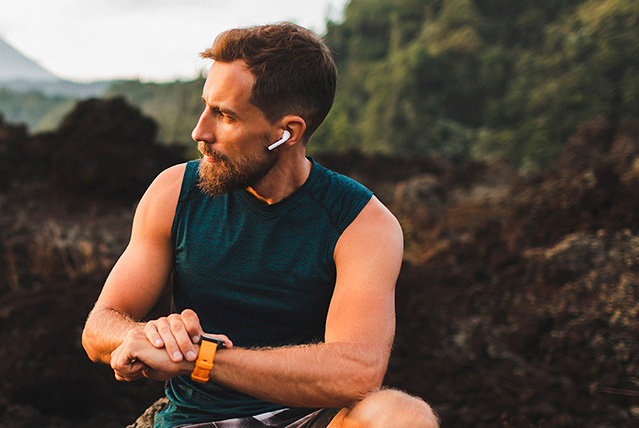 An athlete is sitting outdoors, looking to the left and adjusting their Suunto watch.